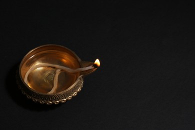 Photo of Lit diya on dark background, space for text. Diwali lamp
