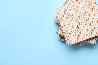 Stack of traditional matzos on light blue background, top view. Space for text