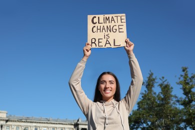 Young woman with poster protesting against climate change outdoors