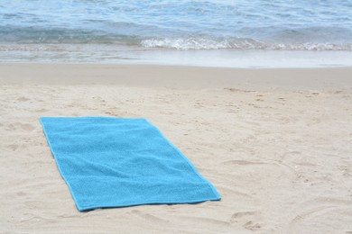 Blue towel on sandy beach near sea, space for text