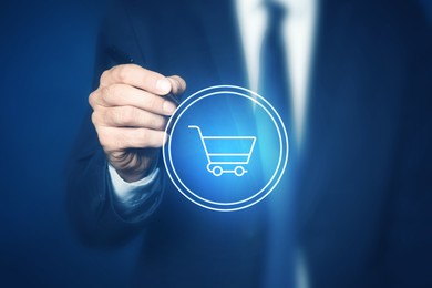 Man pointing at icon of shopping cart on virtual screen, closeup. Online store