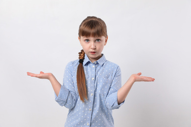 Portrait of confused little girl on white background. Thinking about answer for question