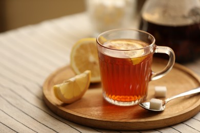 Photo of Glass mug of aromatic tea with lemon and sugar on table, closeup. Space for text