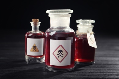 Bottles with poison on black wooden table