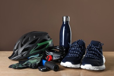 Different cycling accessories on wooden table against brown background