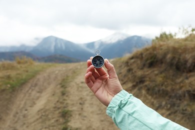 Woman using compass during journey in mountains, closeup