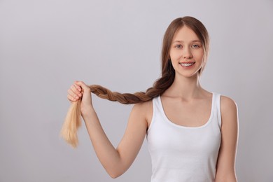 Teenage girl with strong healthy braided hair on light grey background