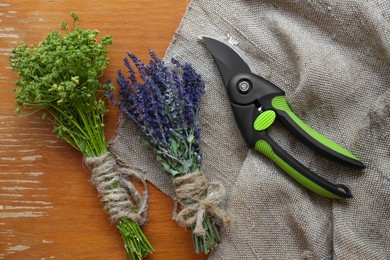 Secateur, lavender and wild flowers on wooden table, flat lay