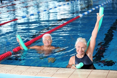 Sportive senior couple doing exercises in indoor swimming pool