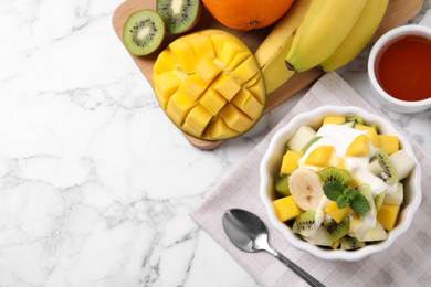 Delicious fruit salad on white marble table, flat lay. Space for text