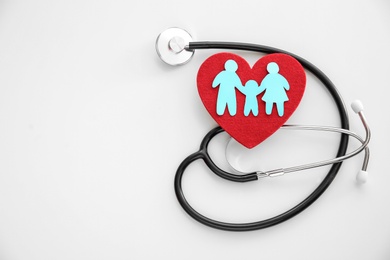 Flat lay composition with paper family cutout, red heart and stethoscope on light background