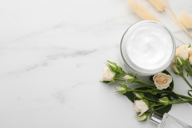 Jar of hand cream and roses on white marble table, flat lay. Space for text