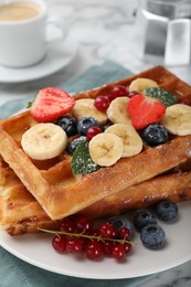 Photo of Delicious Belgian waffles with berries and banana on plate, closeup