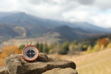 Compass on rock in mountains, space for text