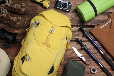 Flat lay composition with backpack and other different camping equipment for tourism on wooden background