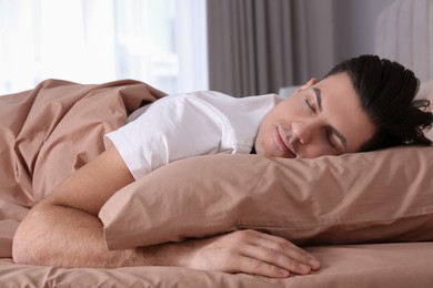 Man sleeping in comfortable bed with beige linens