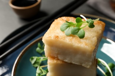 Delicious turnip cake with microgreens served on plate, closeup