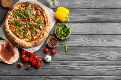 Tasty pizza with meat and arugula on grey wooden table, flat lay. Space for text