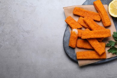Fresh breaded fish fingers served on grey table, top view. Space for text