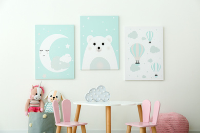 Photo of Adorable wall art, table and chairs with bunny ears in children's room interior