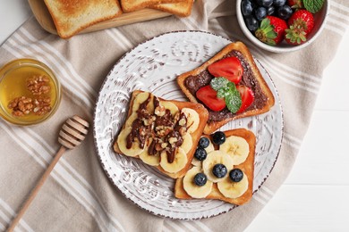 Different sweet delicious toasts served on white wooden table, flat lay
