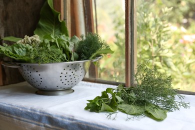 Photo of Different herbs in colander near window indoors