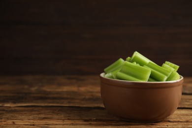 Photo of Cut celery in bowl on wooden table. Space for text