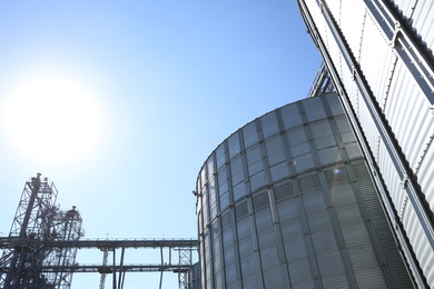 Photo of Modern granaries for storing cereal grains against blue sky, low angle view