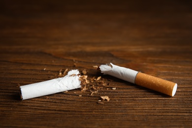 Broken cigarette on wooden table, closeup. Quitting smoking concept