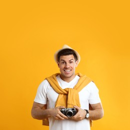 Excited male tourist with camera on yellow background