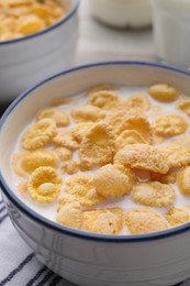 Tasty cornflakes with milk in bowl on table, closeup