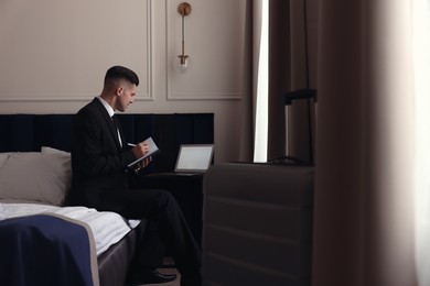 Handsome businessman working on bed in hotel room