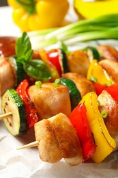 Delicious chicken shish kebabs with vegetables on parchment, closeup