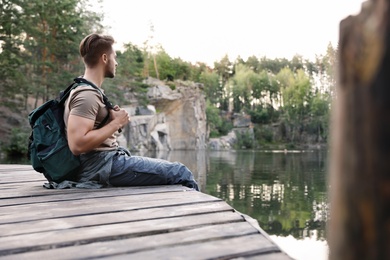 Photo of Young man on wooden pier near lake. Camping season