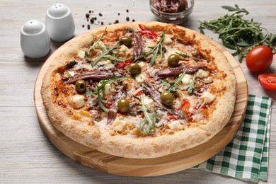 Photo of Tasty pizza with anchovies and ingredients on grey wooden table