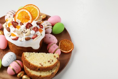 Photo of Traditional Easter cake with dried fruits and painted eggs on white table, space for text