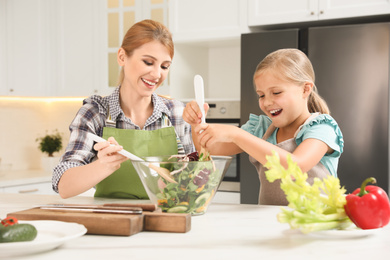 Mother and daughter cooking salad together in kitchen