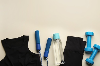 Flat lay composition with sportswear and equipment on beige background, space for text. Gym workout