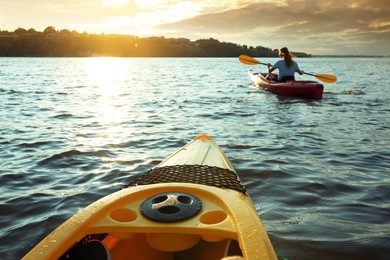 Woman kayaking on river at sunset, view from other boat. Summer activity