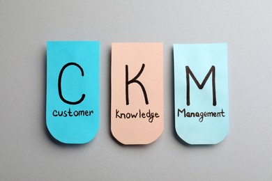 Photo of Notes with abbreviation CKM (Customer Knowledge Management) on light background, flat lay