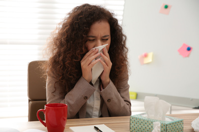 Sick African-American woman at workplace. Influenza virus