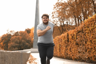 Young overweight man running in park. Fitness lifestyle