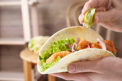 Woman squeezing lime on fish taco indoors, closeup
