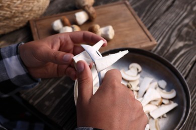 Man slicing mushrooms at wooden table, closeup