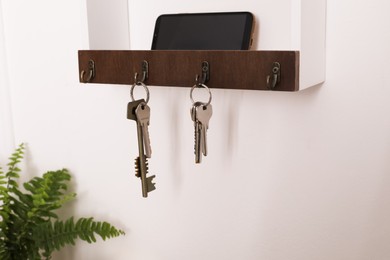 Wooden hanger for keys on white wall