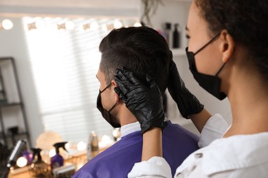 Professional stylist working with client in salon, closeup. Hairdressing services during Coronavirus quarantine