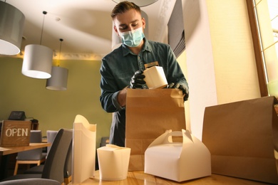 Waiter packing takeout order in restaurant. Food service during coronavirus quarantine