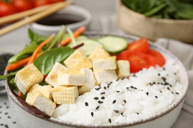 Photo of Delicious poke bowl with vegetables, tofu and mesclun, closeup