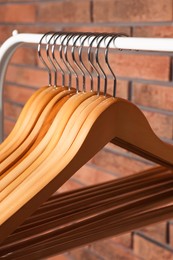 Wooden clothes hangers on rack near red brick wall, closeup