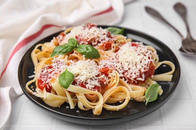 Delicious pasta with tomato sauce, basil and parmesan cheese on white tiled table, closeup